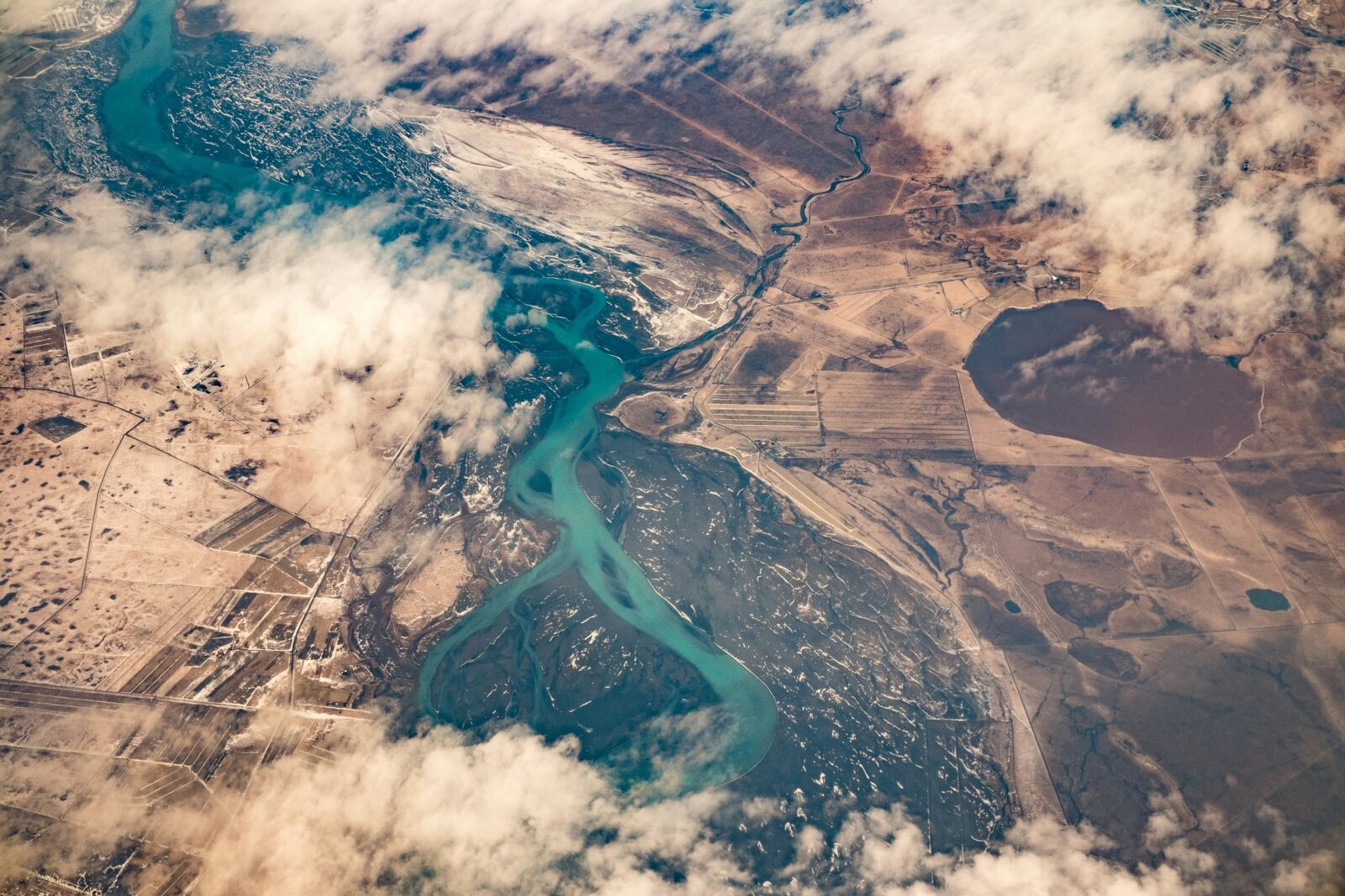 An aerial view of a river and surrounding brown landscape. Photo by Anders Jilden on Unsplash.