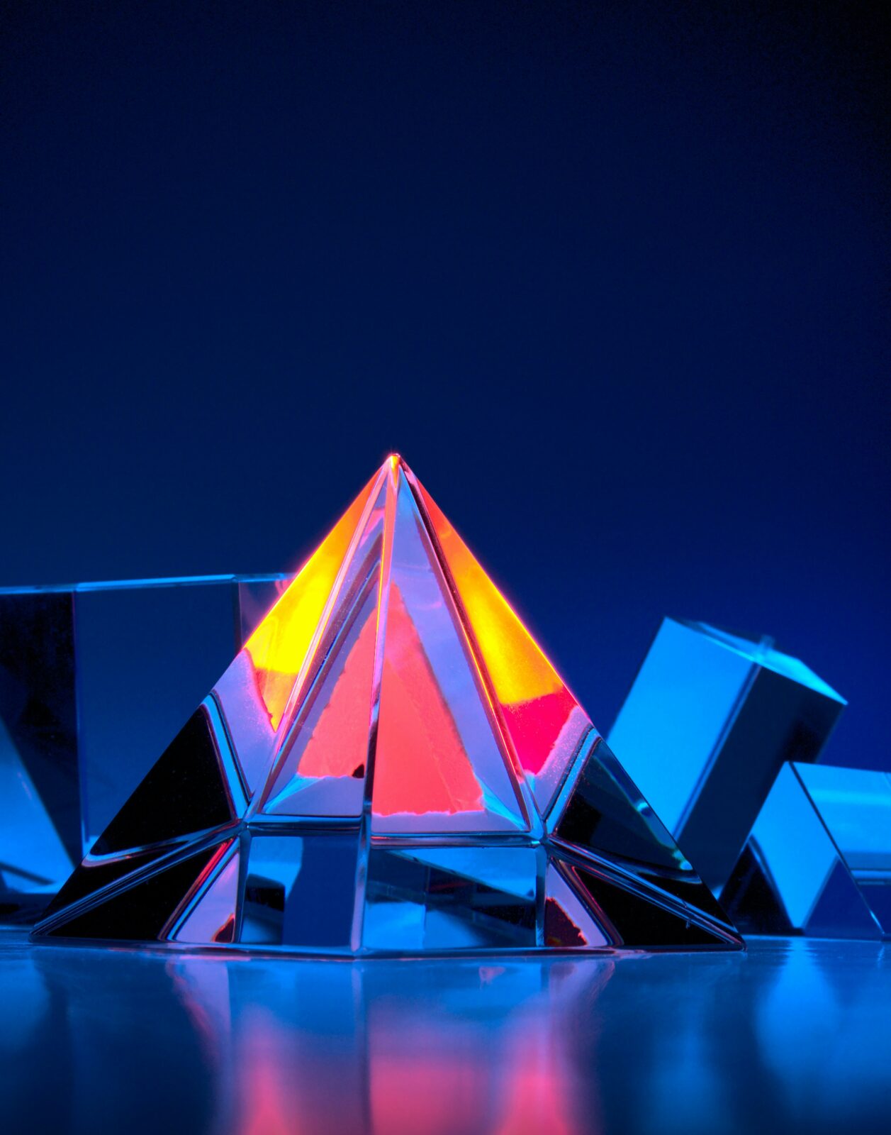 Photograph of colored glass objects, centered around a pyramid. Photo by Michael Dziedzic on Unsplash