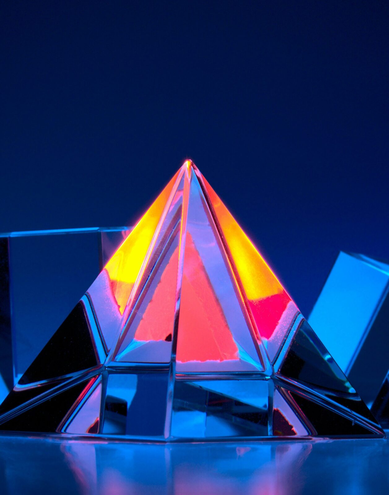 Photograph of colored glass objects, centered around a pyramid. Photo by Michael Dziedzic on Unsplash
