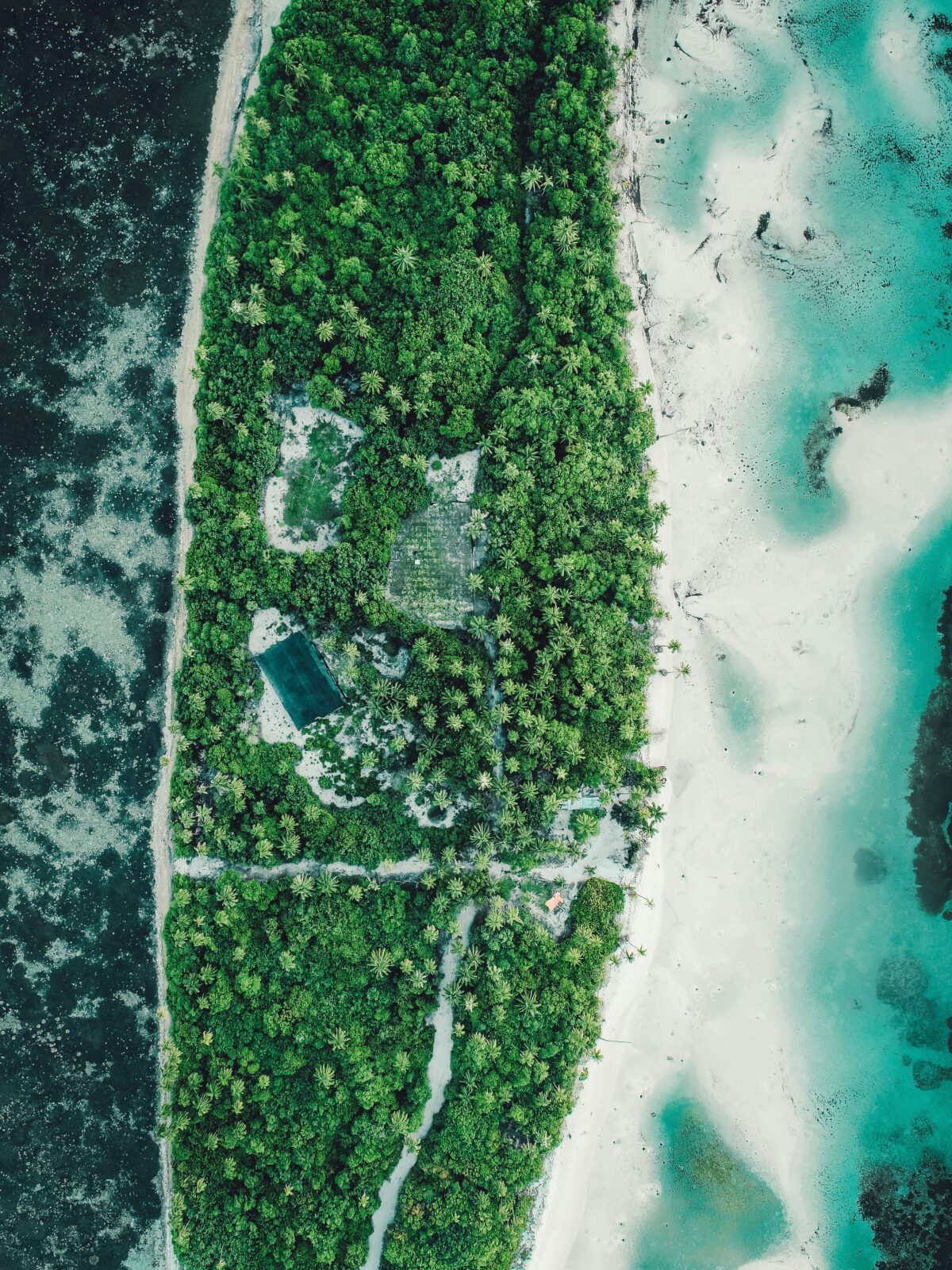 An aerial view of a road running along a beach with trees between the road and beach. Photo by Hamdhulla Shakeeb on Unsplash.